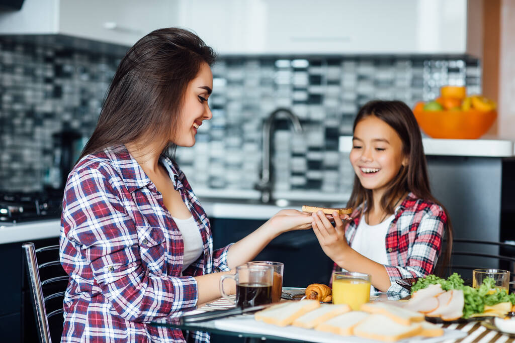 Aliments sains à la maison. Bonne famille dans la cuisine. Mère et fille d'enfant prennent le petit déjeuner avec sandwich. - Photo, image