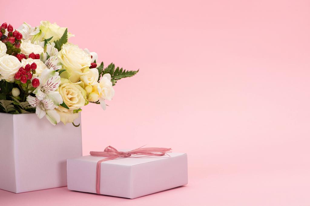 buquê de flores em caixa de presente festivo com arco sobre fundo rosa
 - Foto, Imagem