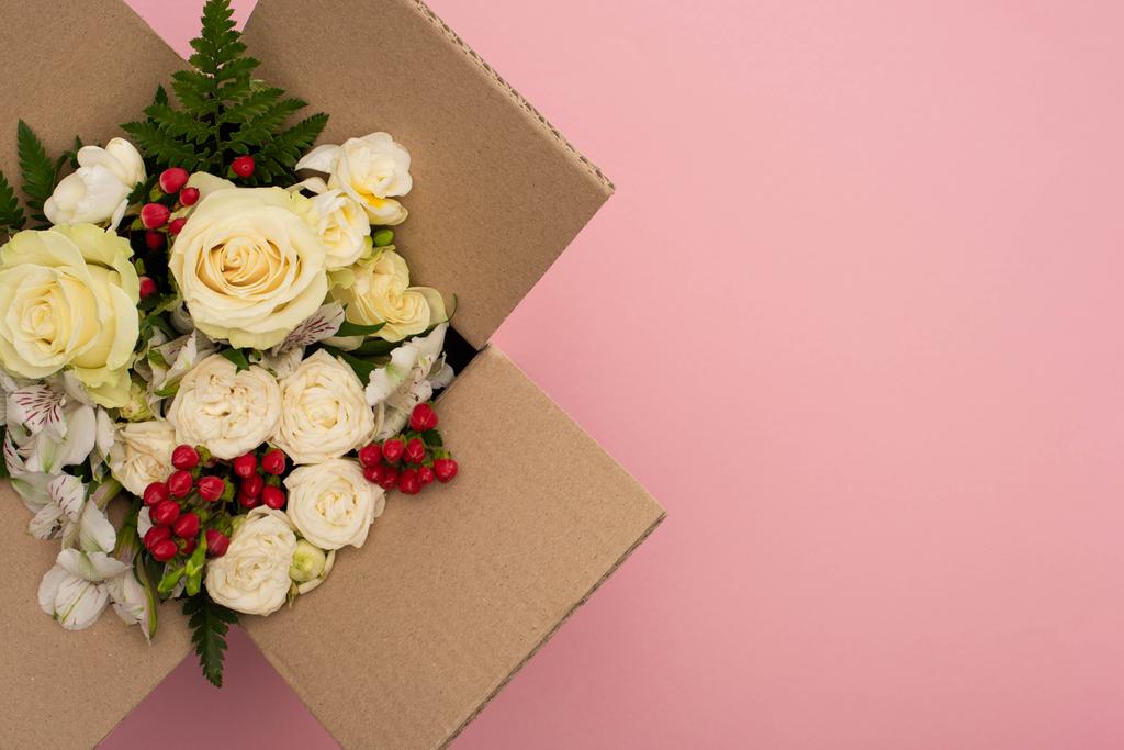 вид на букет цветов в картонной коробке на розовом фоне
 - Фото, изображение