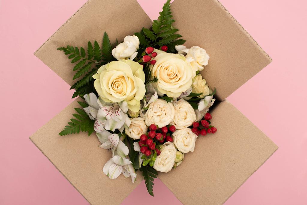 top view of bouquet of flowers in cardboard box on pink background - Photo, Image