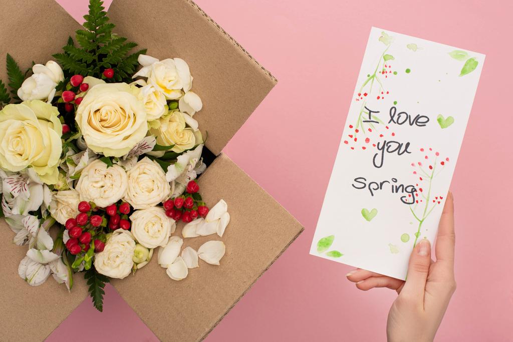 kivágott kilátás nő gazdaság szeretlek tavaszi kártya közelében csokor virágok kartondobozban rózsaszín háttér - Fotó, kép