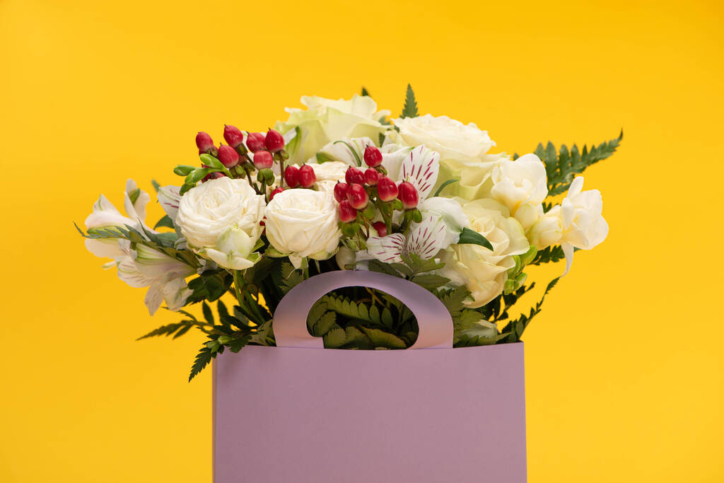 bouquet de fleurs fraîches printanières en sac de papier violet isolé sur jaune
 - Photo, image