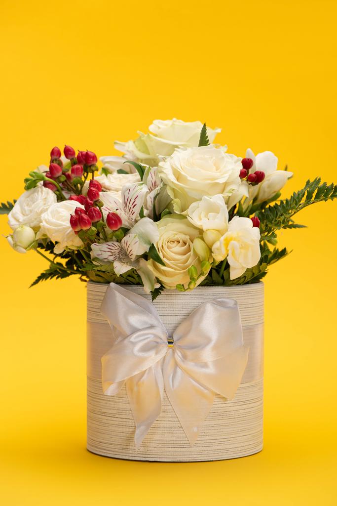 весенний свежий букет цветов в праздничной подарочной коробке с бантом на желтом
 - Фото, изображение