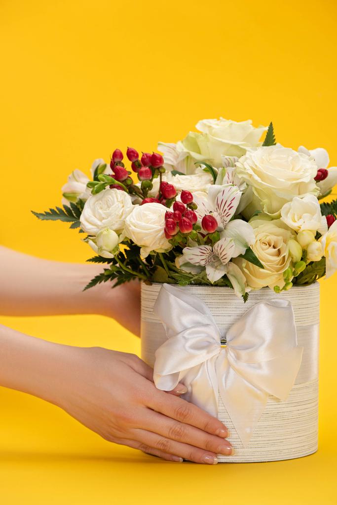cropped view of woman holding spring fresh bouquet of flowers in festive gift box with bow on yellow - Photo, Image