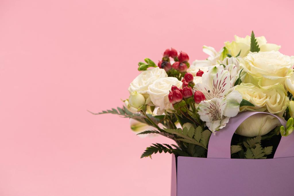 μπουκέτο λουλούδια σε βιολετί χάρτινη σακούλα που απομονώνονται σε ροζ - Φωτογραφία, εικόνα