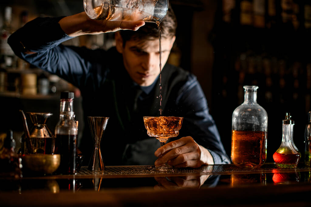 Il barman versa un cocktail da un bicchiere all'altro
. - Foto, immagini