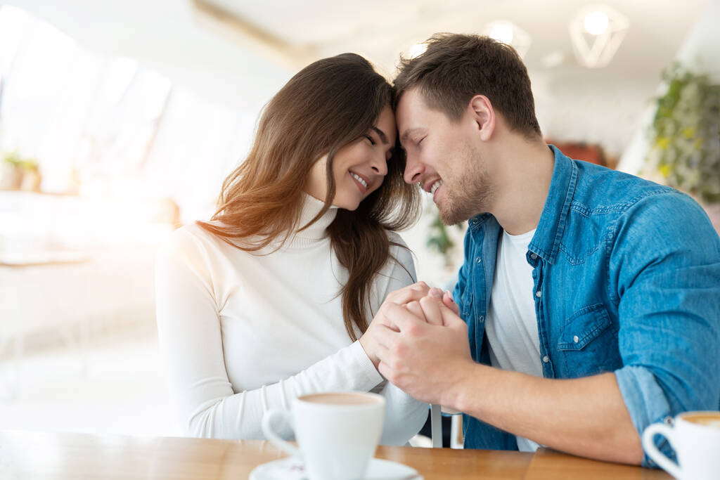 fiatal pár gyönyörű nő kéz a kézben az ő jóképű férfi szerelmes, miközben kávézóban ebéd közben, szerelem és gyengédség koncepció. - Fotó, kép