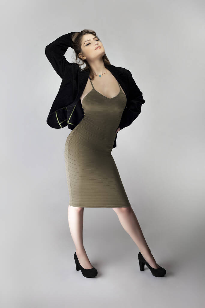 Modelo feminino posando como uma mulher de negócios sexy que parece confiante como um chefe ou um gerente. Sua roupa é um vestido marrom ou bronzeado na moda com um terno de negócios ou jaqueta
.  - Foto, Imagem