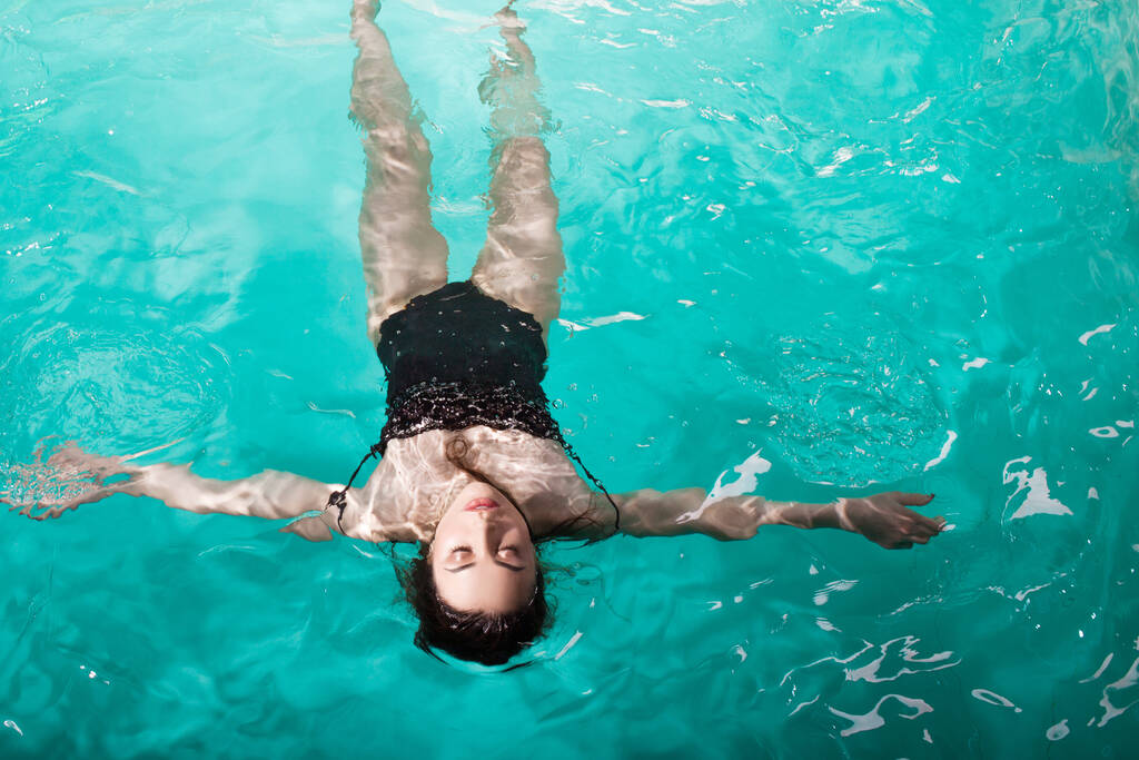 bella ragazza è rilassante nella piscina Spa, nuotare e rilassarsi. giovane donna galleggiante in acqua sul retro
, - Foto, immagini
