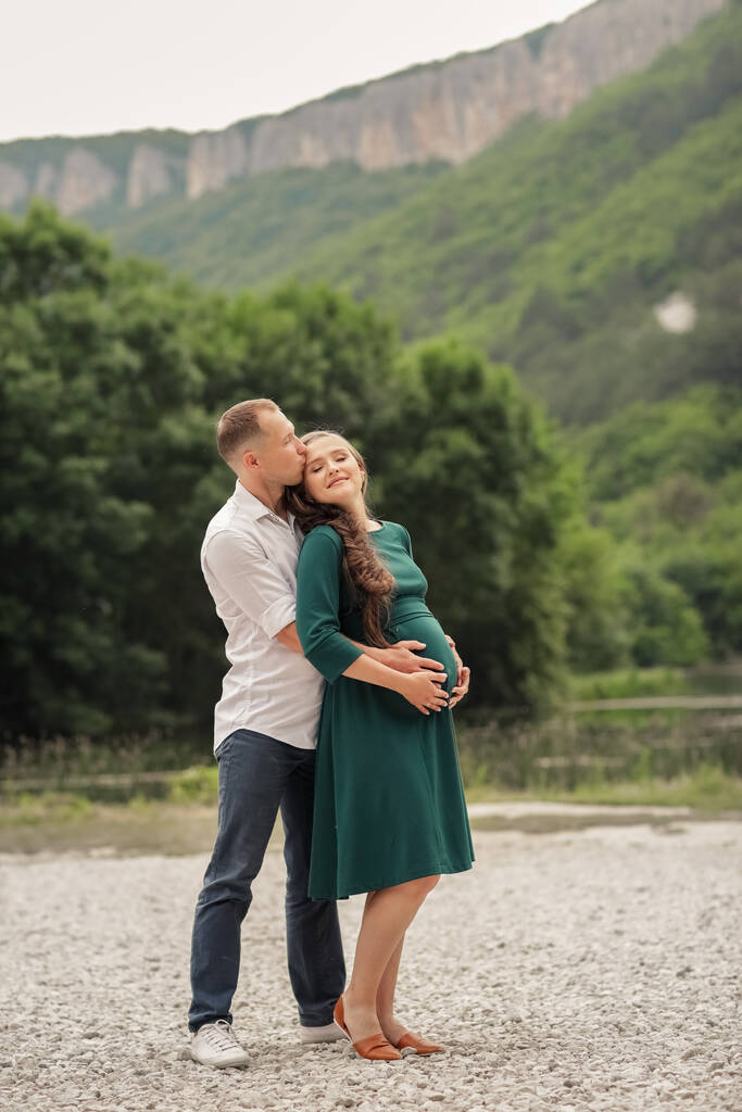 Férfi ölel terhes feleség közepette hegyek és tavak - Fotó, kép