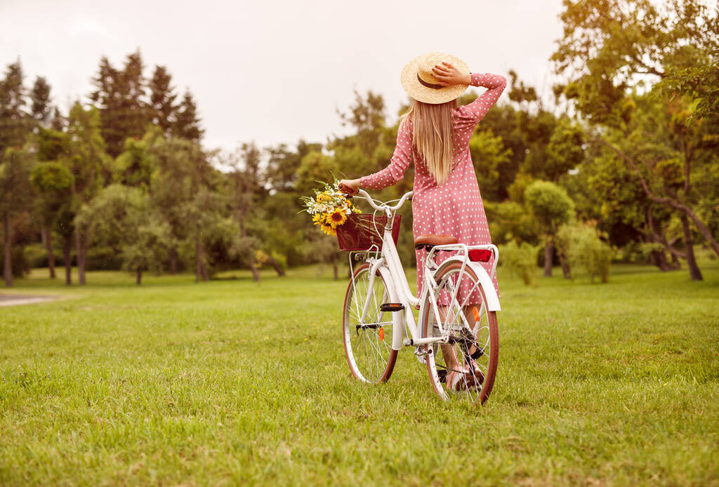 Anonymous woman with bicycle enjoying sunny day in park - Φωτογραφία, εικόνα