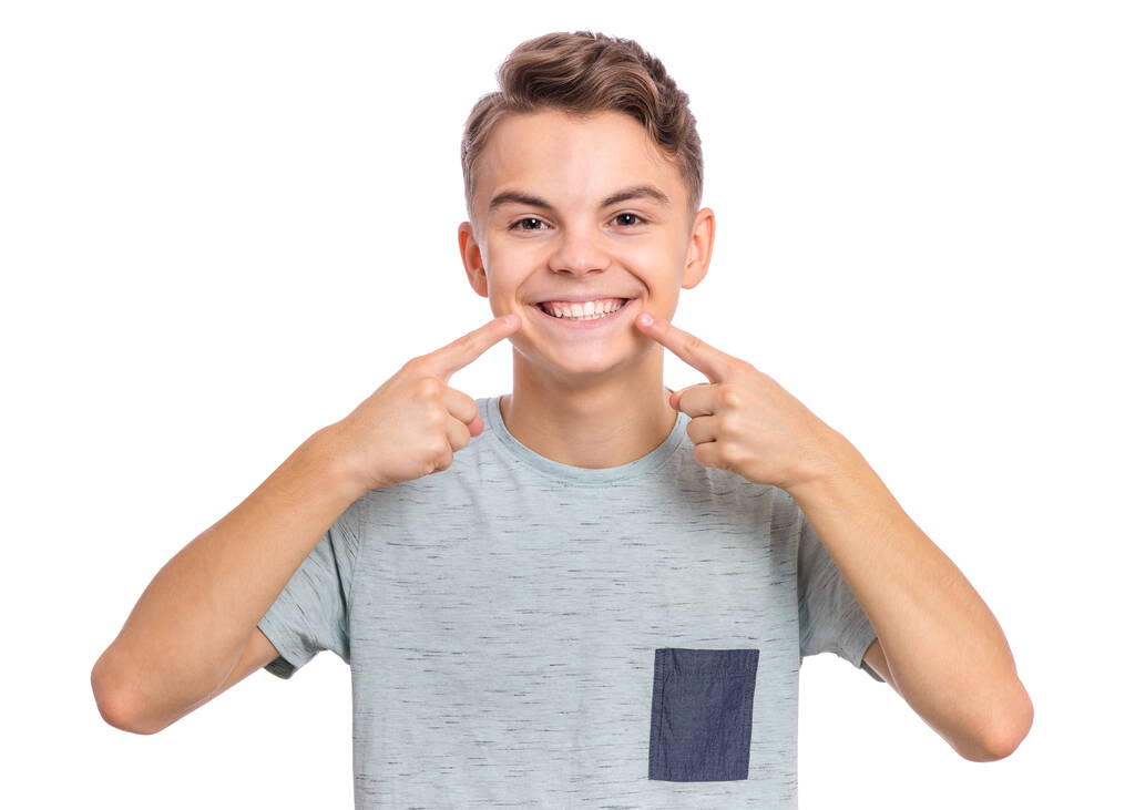 Portrait of teen boy showing his teeth. Child pointing with finger teeth and mouth. Caucasian young teenager, isolated on white background. Concept of good teeth care. Dental health concept. - Photo, Image