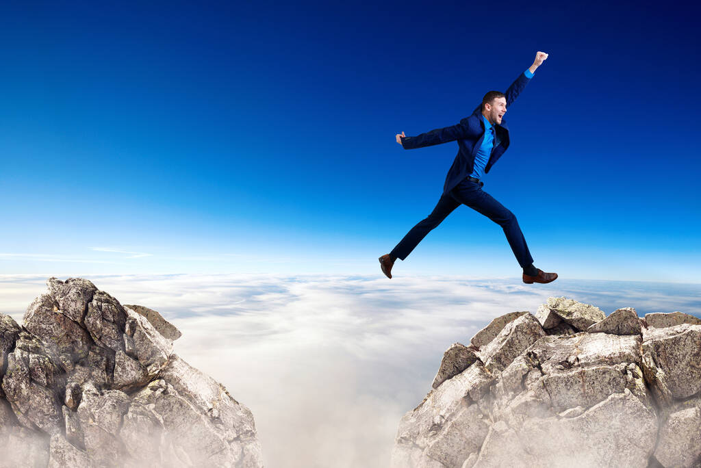 Young businessman flying through the gap among mountains. - Photo, Image