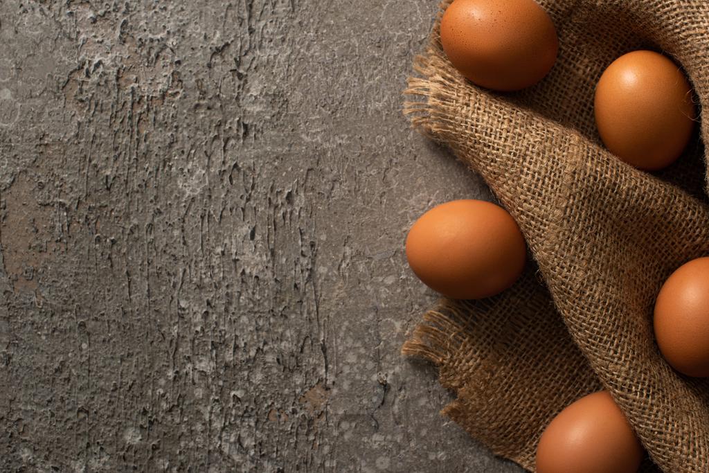 felső nézet barna tojás zsákvászon szürke texturált háttér - Fotó, kép