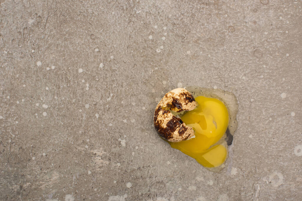 vrchní pohled na rozbité křepelčí vejce na šedém betonovém pozadí - Fotografie, Obrázek