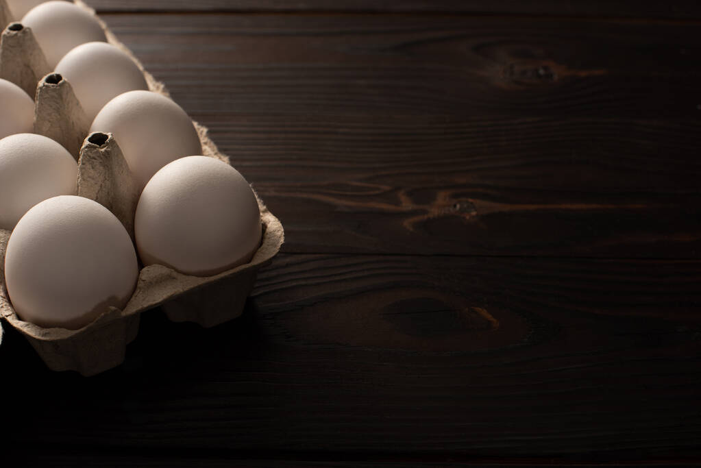 Hühnereier im Eierfach auf dunkler Holzoberfläche  - Foto, Bild