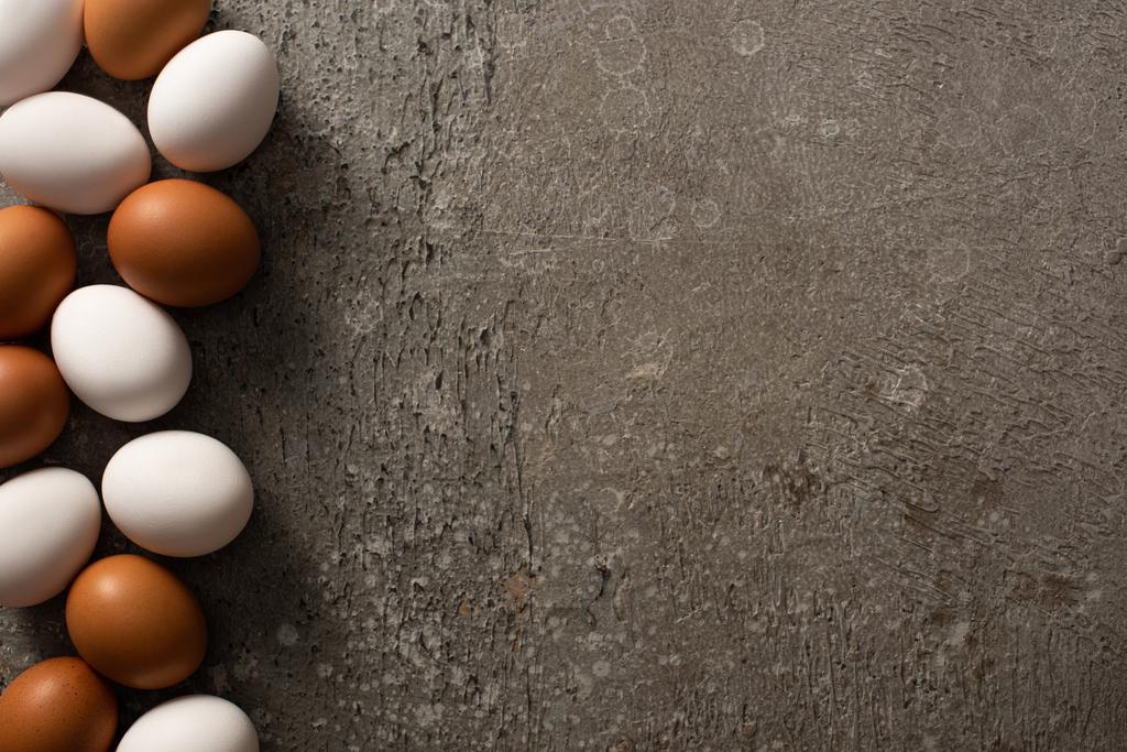 вид зверху на коричневі та білі курячі яйця на сірому бетонному фоні
 - Фото, зображення