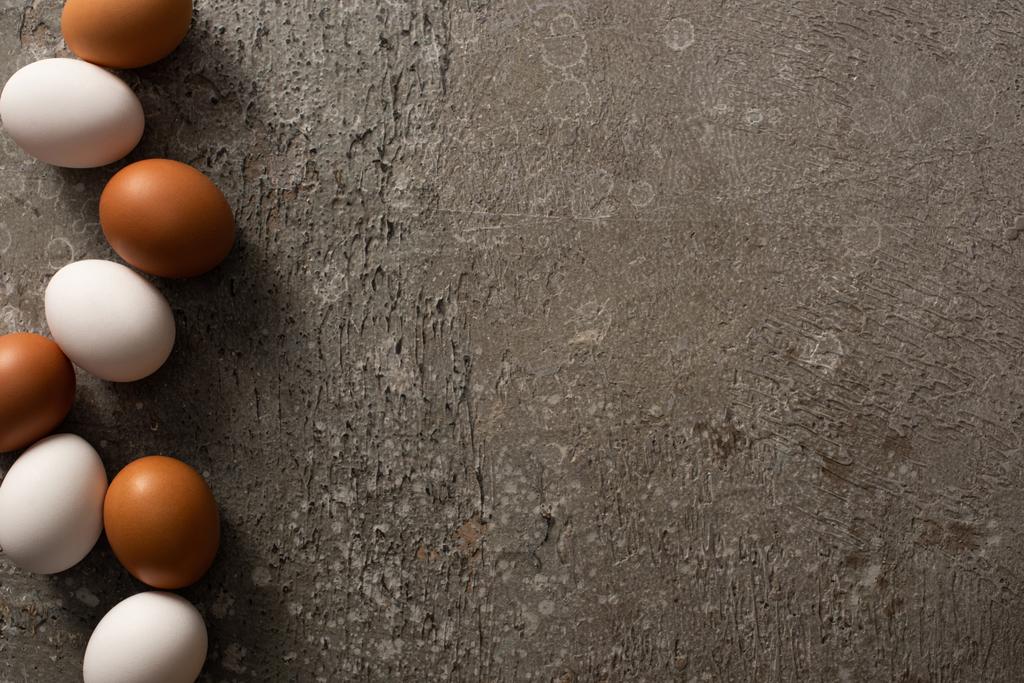 bovenaanzicht van bruine en witte kippeneieren op grijze textuur achtergrond - Foto, afbeelding