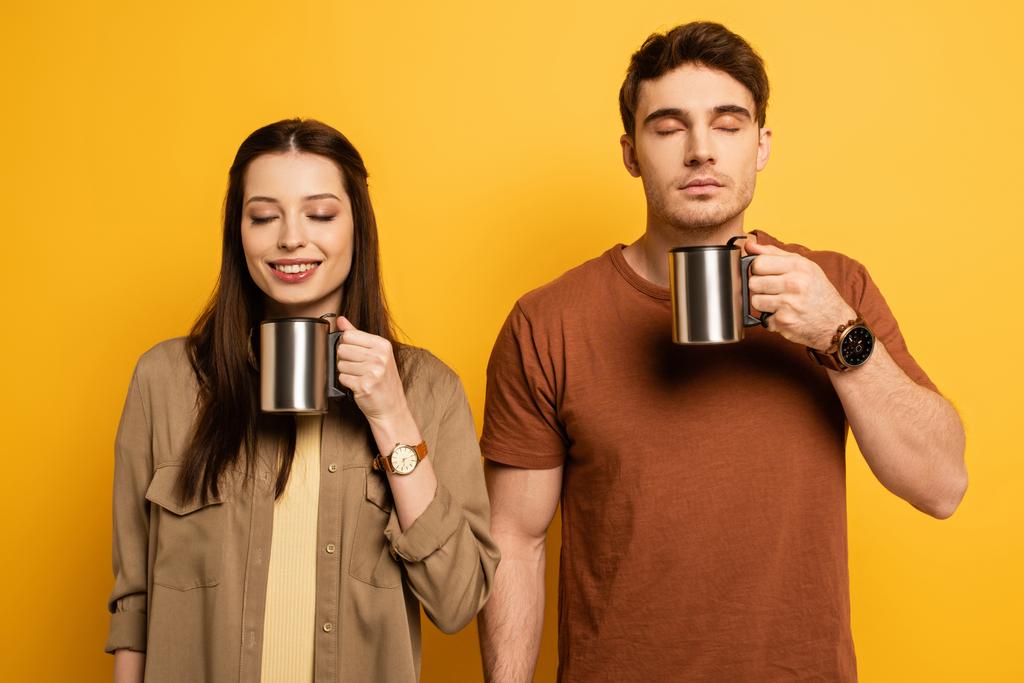 пара щасливих туристів тримає чашки кави із задоволенням на жовтому
 - Фото, зображення