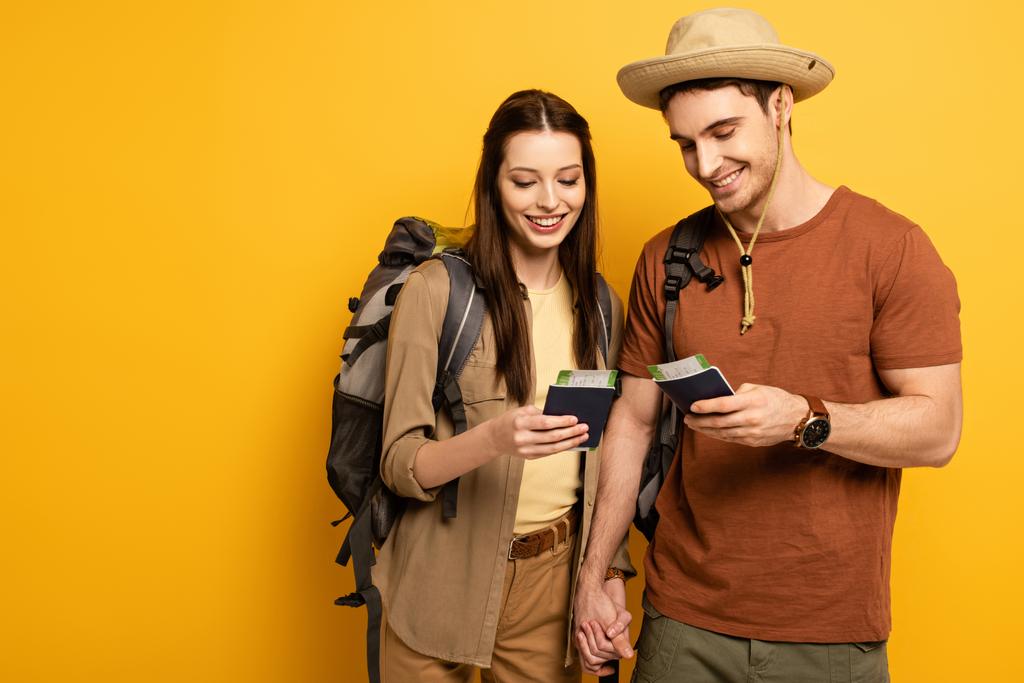 casal de viajantes felizes com mochilas segurando passaportes e bilhetes em amarelo
 - Foto, Imagem