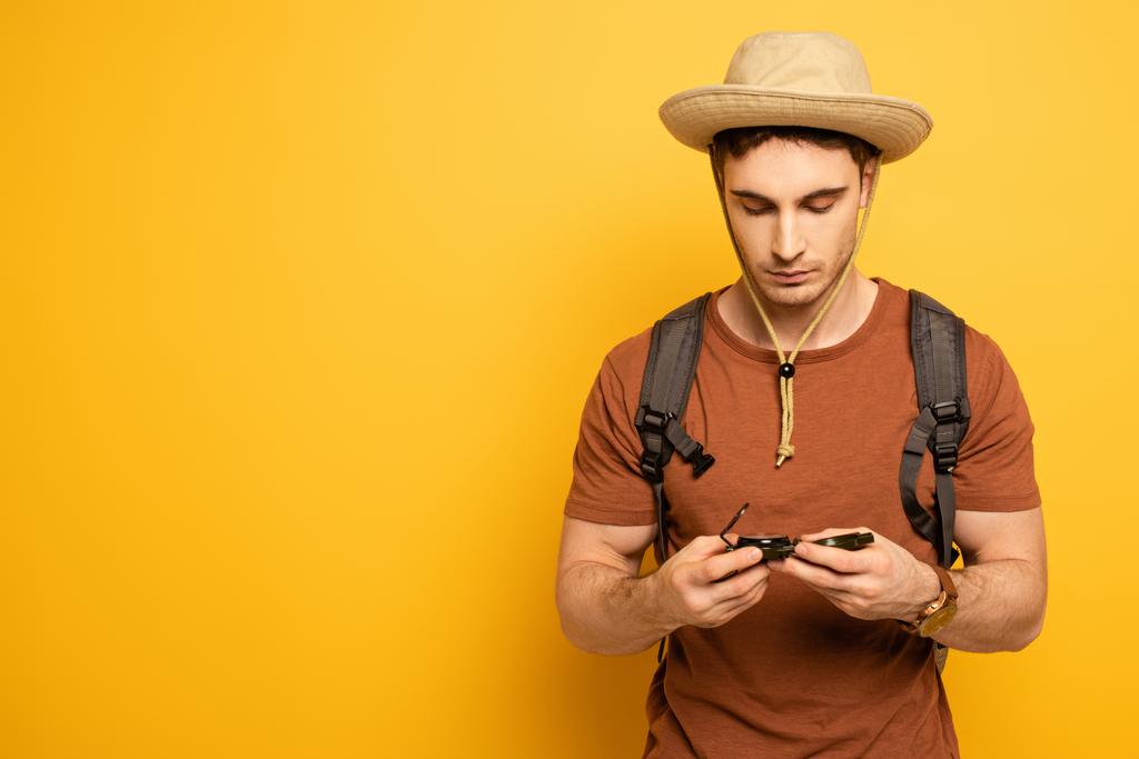 handsome traveler looking at compass on yellow - Photo, Image