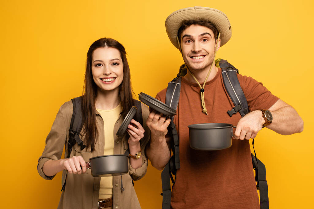 couple de touristes joyeux avec des sacs à dos tenant des pots sur jaune
 - Photo, image