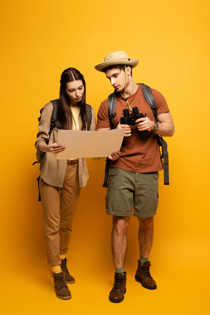 couple de touristes avec sacs à dos et jumelles regardant la carte sur jaune
 - Photo, image