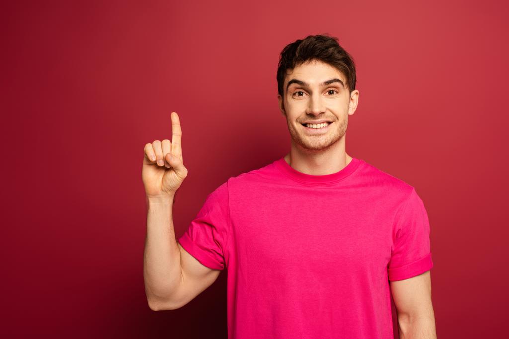 портрет усміхненого чоловіка в рожевій футболці, що вказує на червоний
 - Фото, зображення
