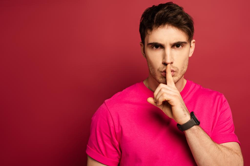 πορτρέτο του ανθρώπου σε ροζ t-shirt που δείχνει το σύμβολο της σιωπής στο κόκκινο - Φωτογραφία, εικόνα