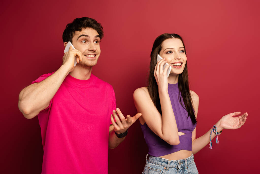 kaunis emotionaalinen pari puhuu älypuhelimissa punaisella
 - Valokuva, kuva