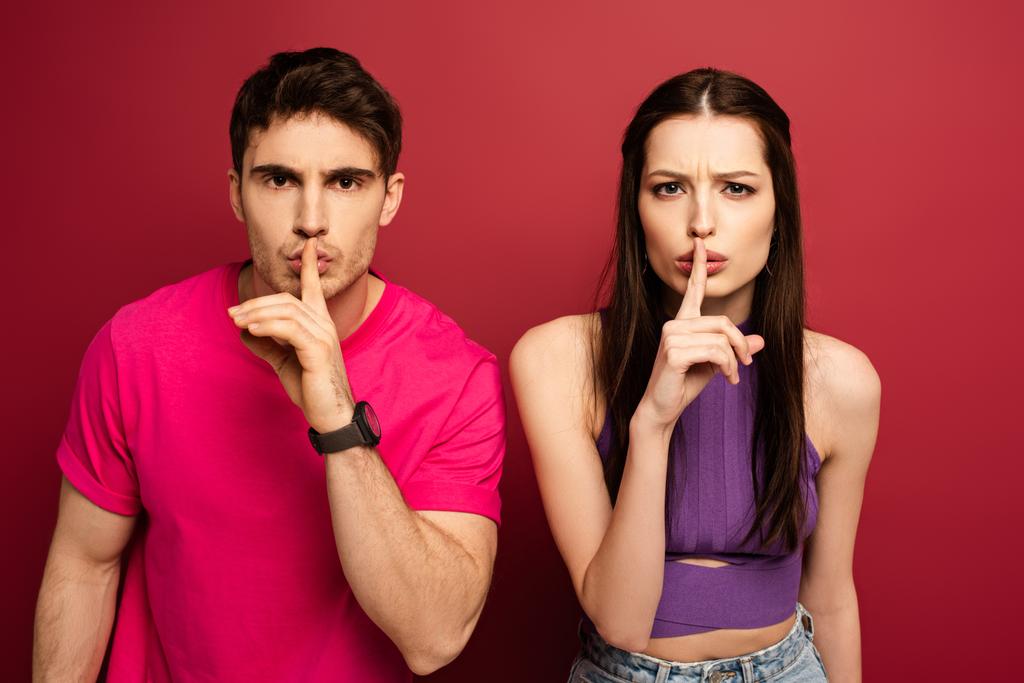 beautiful young couple showing silence symbols on red - Photo, Image