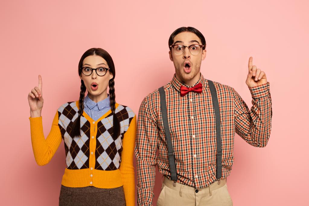 par de nerds sorprendidos en gafas teniendo idea y apuntando hacia arriba en rosa
 - Foto, Imagen