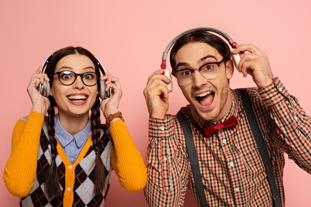 ピンクのヘッドフォンで音楽を聴く眼鏡の興奮した神経のカップル ロイヤリティフリー写真 画像素材