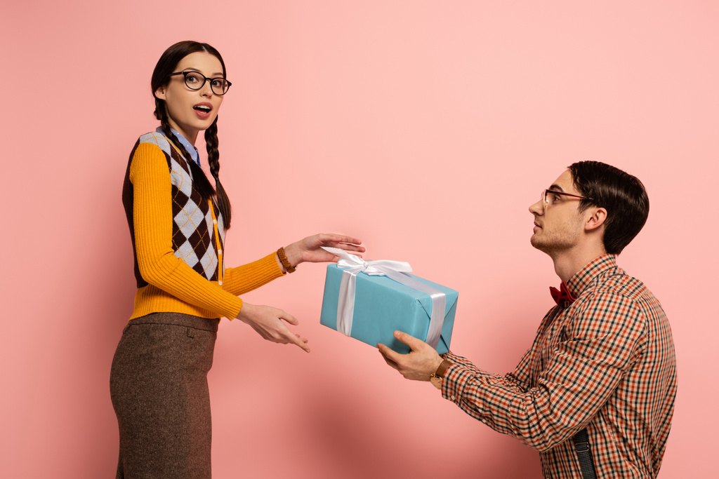 pohledný nerd dávat dárek překvapené přítelkyně na růžové - Fotografie, Obrázek
