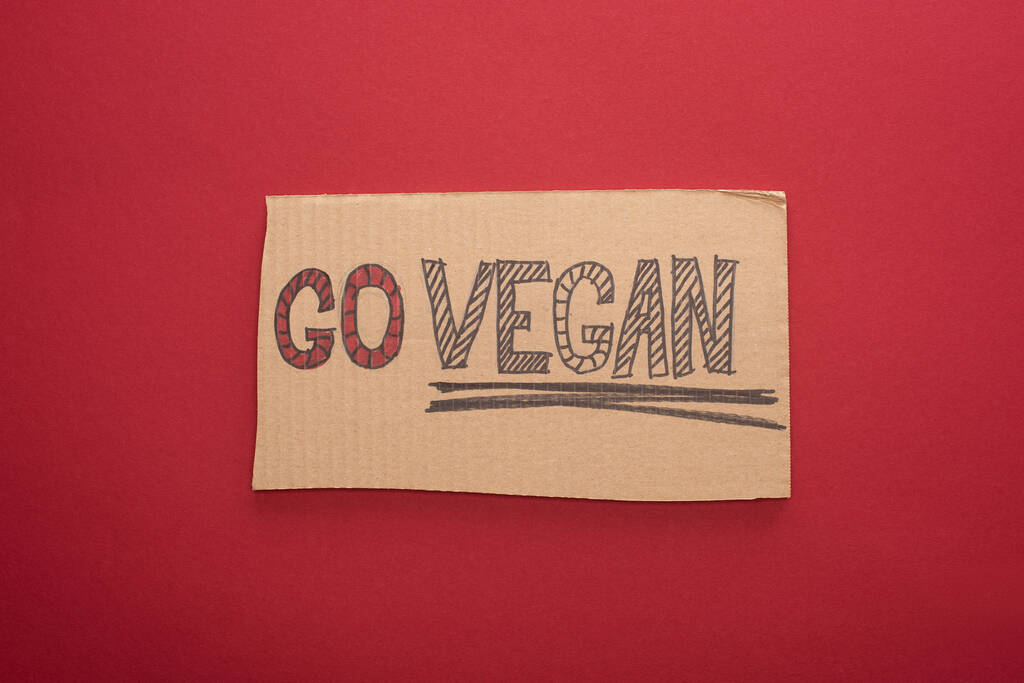 von oben auf Pappschild mit veganer Aufschrift auf rotem Hintergrund - Foto, Bild