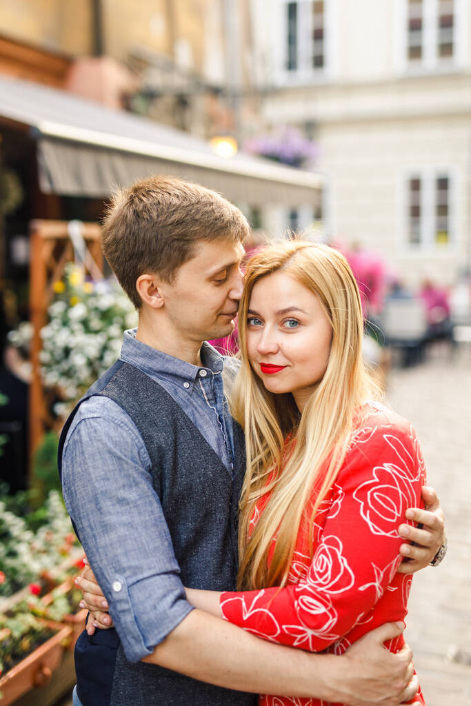 una joven pareja está elegantemente vestida, una chica con un vestido rojo, un hombre con una camisa azul y pantalones azules, caminar por las calles en Cracovia Polonia
 - Foto, Imagen