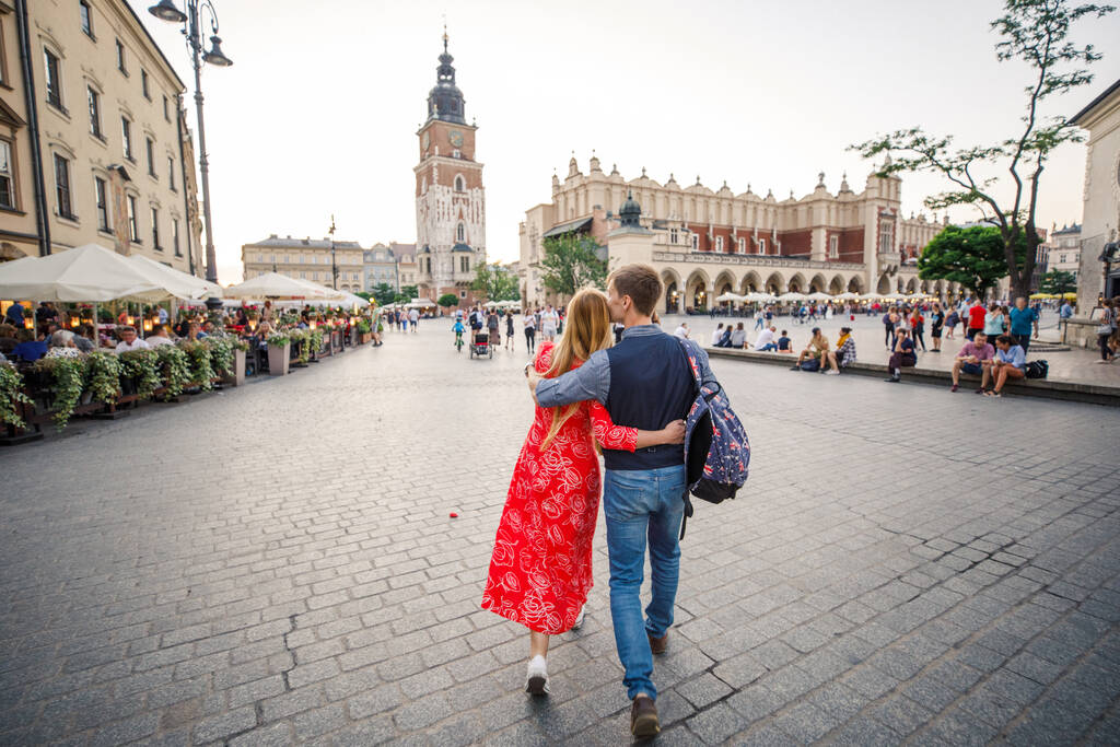 mladý pár je stylově oblečený, dívka v červených šatech, muž v modré košili a modrých kalhotách, procházka ulicemi v Krakově Polsko - Fotografie, Obrázek