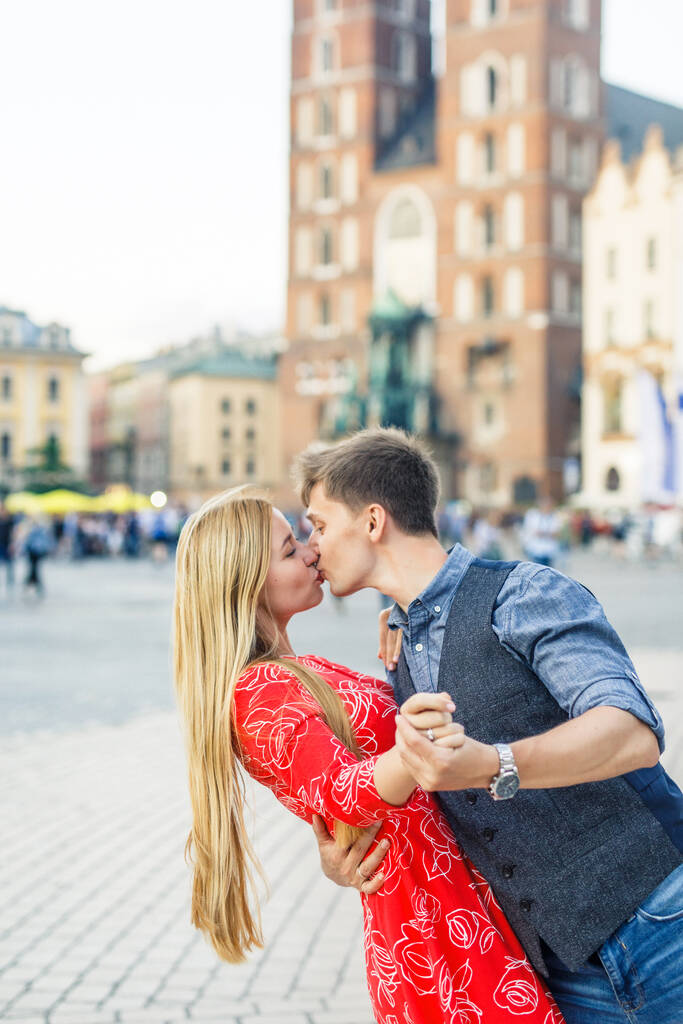 una joven pareja está elegantemente vestida, una chica con un vestido rojo, un hombre con una camisa azul y pantalones azules, caminar por las calles en Cracovia Polonia
 - Foto, imagen
