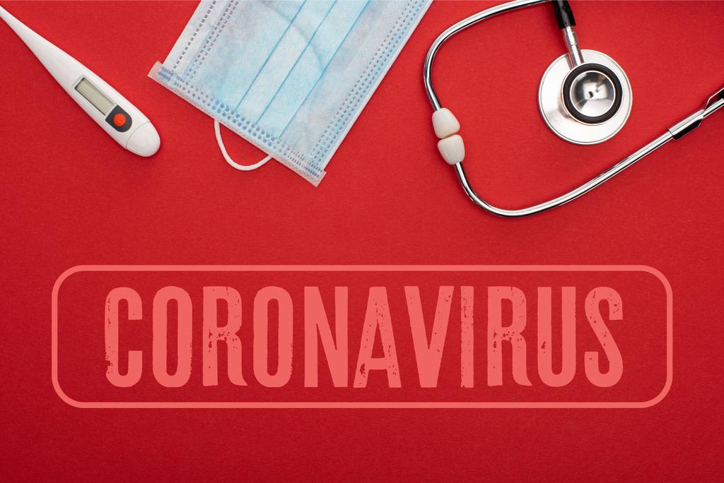 Верхний вид медицинской маски с термометром и стетоскопом на красном фоне с изображением коронавируса
 - Фото, изображение