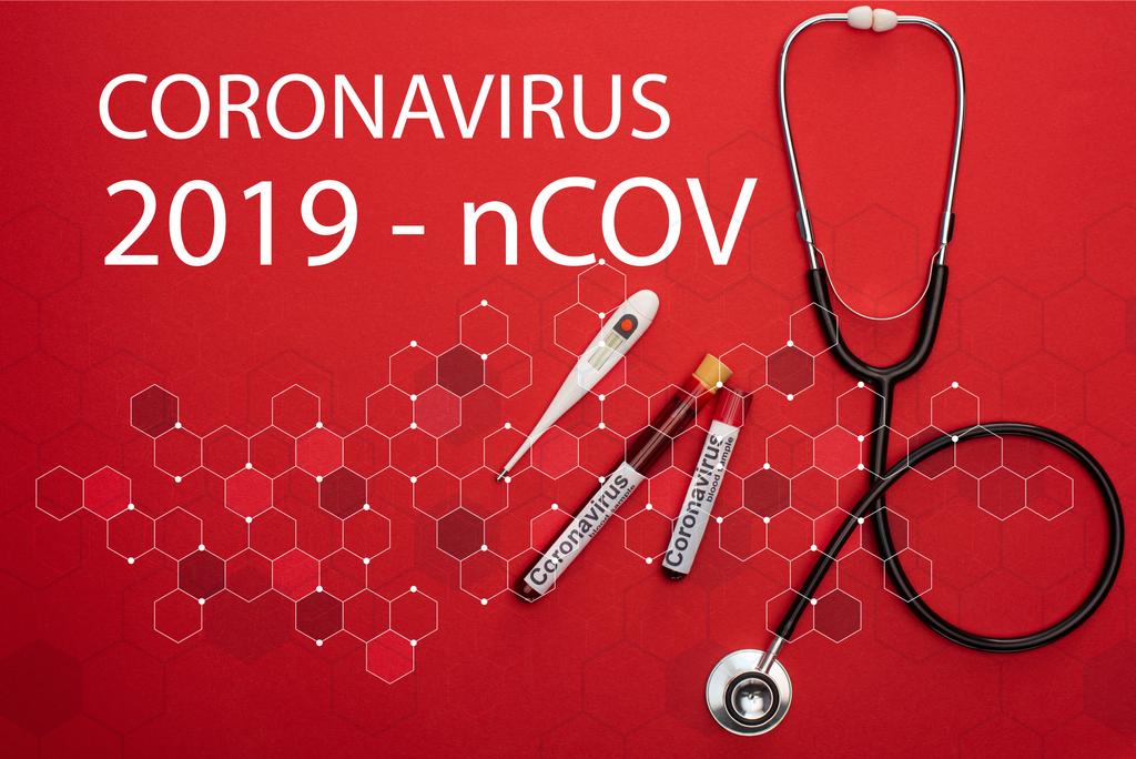 Κάτοψη του στηθοσκοπίου, του θερμόμετρου και των δοκιμαστικών σωλήνων με δείγματα αίματος και γράμματα coronavirus 2019-ncov σε κόκκινο φόντο - Φωτογραφία, εικόνα