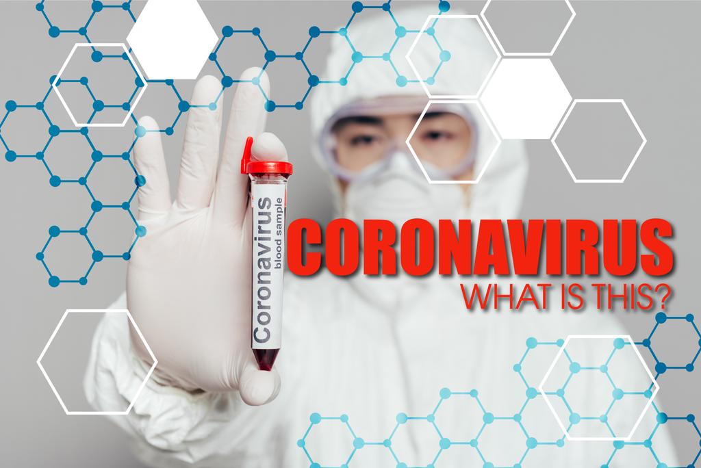 Tehlikeli madde giysisi ve solunum maskesi içinde Asyalı epidemiyologların seçici odak noktası gri arka planda kan örneği ve koronavirüs çizimi gösteren test tüpü gösteriyor.  - Fotoğraf, Görsel
