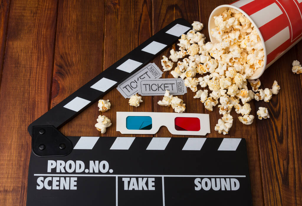 Kinokarten, 3D-Brillen, Pappschachtel verschüttet Popcorn und Filmklöppel auf einem hölzernen Hintergrund - Foto, Bild
