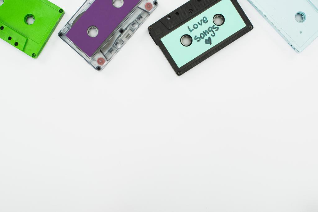 вид сверху на зеленый, фиолетовый и бирюзовый кассеты на белом фоне
 - Фото, изображение
