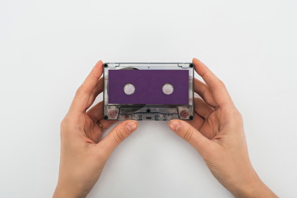 частковий вид людини, що тримає фіолетову касету на білому тлі
 - Фото, зображення