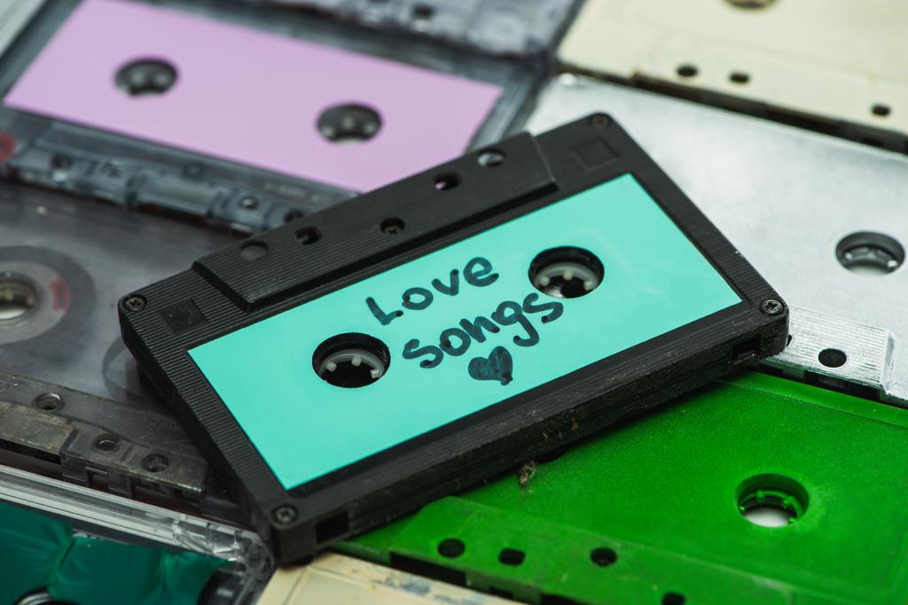 hoge hoek uitzicht van turquoise cassette met liefdesliedjes inscriptie op kleurrijke cassettes - Foto, afbeelding