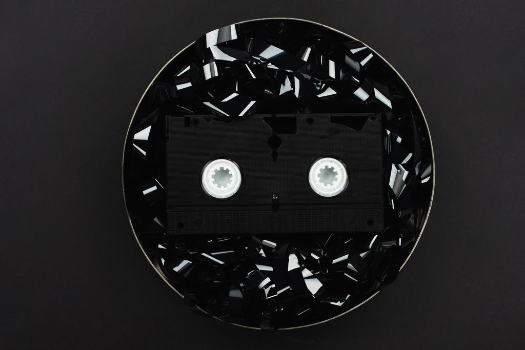 horní pohled na kazetu VHS na černém pruhu v plechovém pouzdře izolovaném na černém - Fotografie, Obrázek