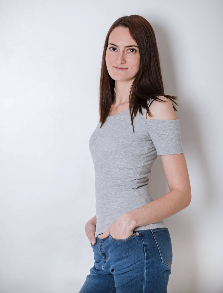 1 Europese, jonge bruinharige vrouw in een grijze top en jeans, portret van een meisje, - Foto, afbeelding