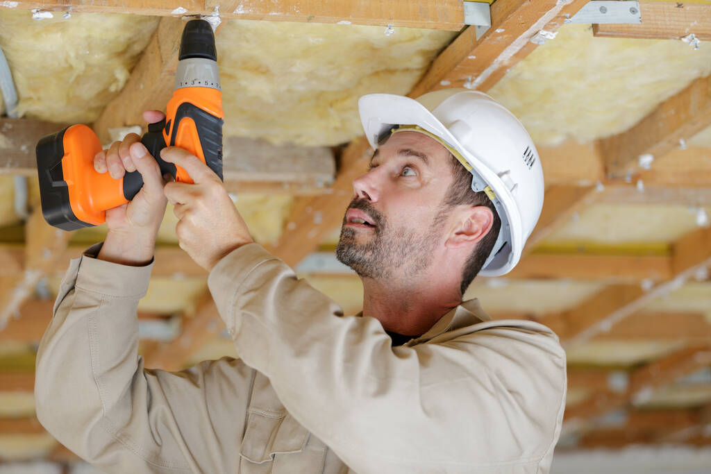 constructeur utilisant perceuse sans fil sur solive de plafond en bois
 - Photo, image