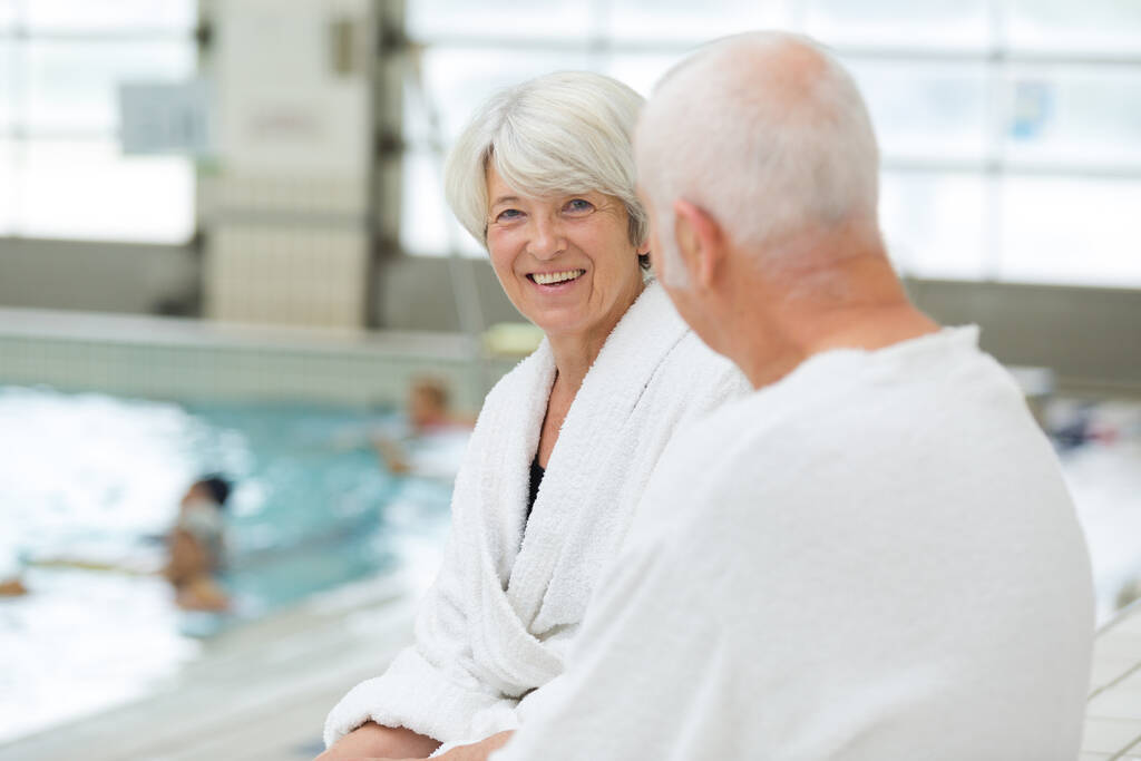 anziani coppia indossa accappatoi seduti a bordo piscina coperta
 - Foto, immagini