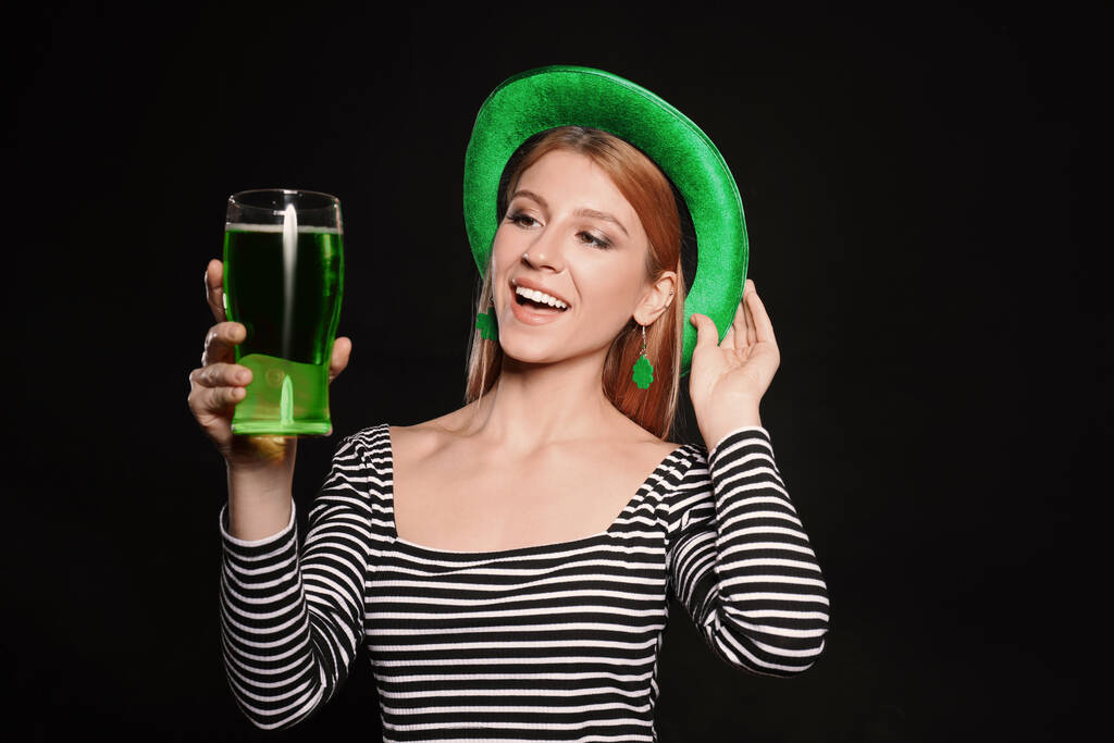 Jeune femme avec bière verte sur fond noir. Célébration de la Saint Patrick
 - Photo, image